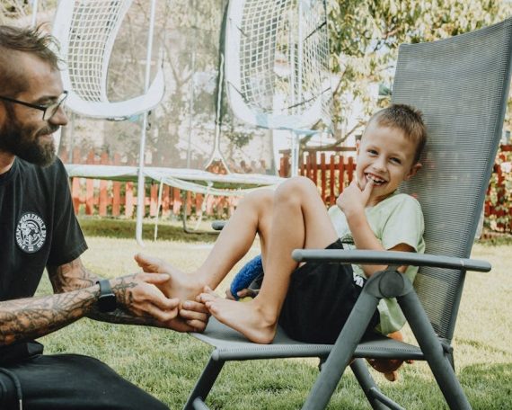 Playful interaction between a father and son in a sunny backyard setting.